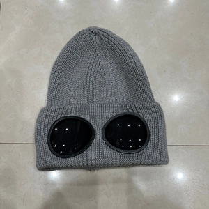 Close-up of dark grey knitted beanie with built-in black goggles on marble surface