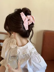 Detail of pink fabric scrunchie with soft pleats on a woman's hair bun
