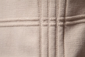 Detailed macro view of the premium light beige knit texture and fine stitching on sweater