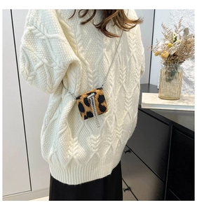 Close-up of mini leopard print crossbody bag with silver chain on a white cable knit sweater