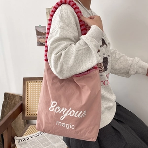 Pink canvas tote bag featuring plush red striped handles and 'Bonjour magic' text