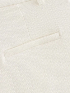 Close-up detail of white woven fabric pocket showing high-quality stitching on trousers
