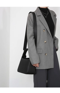 Close-up of black litchi pattern leather shoulder bag with adjustable wide strap on model