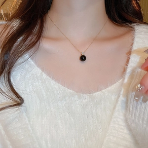 Macro shot of gold necklace with black round pendant and small sparkling diamond