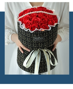 Close-up of red soap roses in a black tweed gift box with pearl and lace details