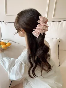 Detailed view of layered pink satin bow hair claw clip styled on long wavy hair
