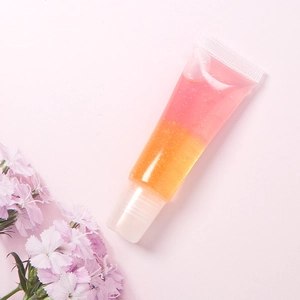 Detalle del tubo de brillo labial bicolore con purpurina y degradado rosa a naranja