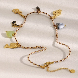 Detail of woven bracelet with 18K gold guitar, music notes, and colorful stone charms