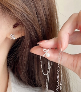Detail of s925 silver percentage symbol necklace and pearl earrings set on model