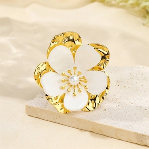 Detail of 18k gold plated flower brooch with pearl petals on natural stone background