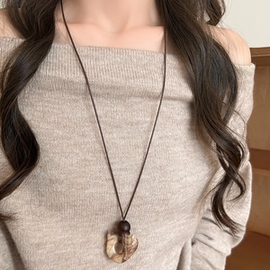 Retro geometric wood and resin pendant necklace styled on a beige knitted sweater