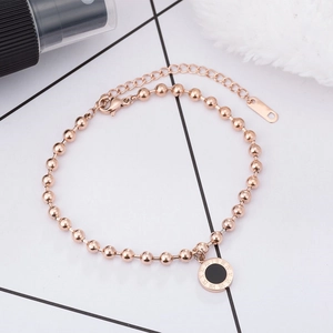 Detail of rose gold beaded bracelet with Roman numeral pendant and black enamel inlay
