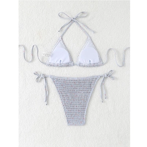 Detailed macro view of light blue smocked bikini set with red floral print on plush rug