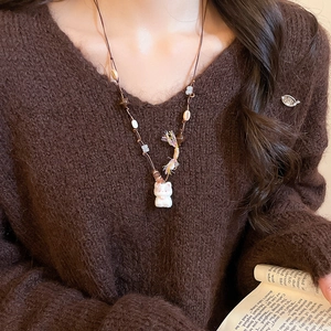 Detailed close-up of beaded star cat pendant with rainbow tassels on a brown knit sweater