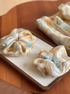 Detailed macro view of ink print pattern on soft fabric scrunchies in a display tray
