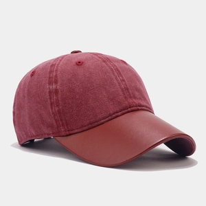 Detail view of burgundy baseball cap with contrast leather brim and washed canvas fabric