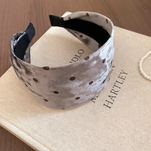 Detail of velvet polka dot wide headband showing fabric texture on a decorative book