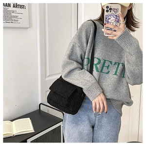 Chic black fuzzy shoulder bag paired with a gray knit sweater and denim jeans