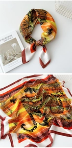 Detail of silk satin scarf with orange leopard print and tropical bird patterns