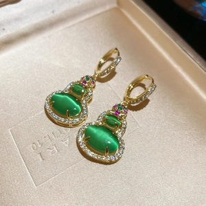 Detail of wulu earrings with green cat eye stone and pave diamonds in 14k gold plating