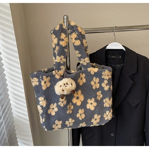 Close-up of blue plush tote bag with yellow floral pattern and cute lamb charm accessory