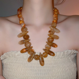 Detail shot of chunky amber resin beads on a bohemian style necklace with glossy texture