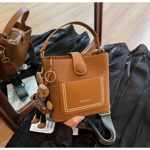 Detail of brown leather bucket bag with gold studs and cute knitted bunny charm