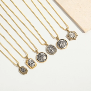 Close-up of vintage gold coin necklaces with Greek goddess and owl engravings on white background