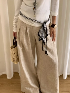 Détail du pantalon large en lin beige avec taille haute plissée et ceinture tressée
