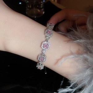 Detailed view of pink square gemstone bracelet on wrist with feather cuff accessory