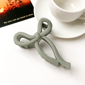 Detailed view of a light green matte bow hair claw clip against a lifestyle background