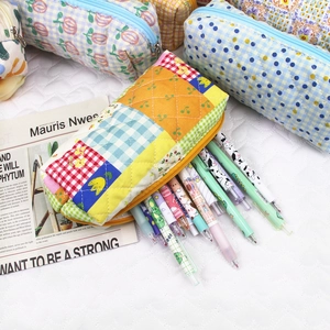 Close-up of quilted floral cotton pouches filled with assorted colorful stationery pens