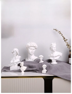 Artistic Greek statues on gray fabric with minimalist decor and dried flowers