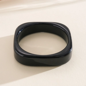 Macro detail of a minimalist black square resin bangle with a high-shine polished finish
