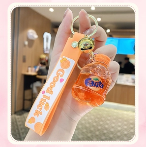 Close-up of a creative orange soda bottle keychain with a Good Luck silicone strap