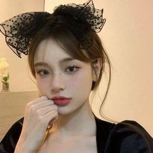 Close-up of a model wearing a large black polka dot mesh bow hair clip in vintage style