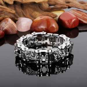 Detail shot of men's stainless steel lion head biker chain bracelet on dark stone background