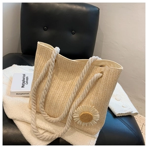 Detail of woven tote bag featuring large daisy applique and dual rope handles on a chair