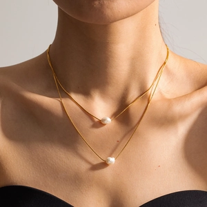 Close-up of double-layer gold titanium steel necklace with irregular pearl pendants