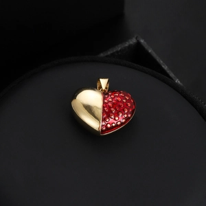 Détail macro du pendentif cœur fraise avec métal doré et émail rouge sur velours noir