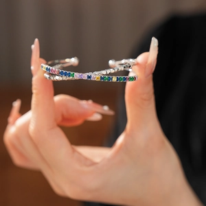 Macro detail of silver cross bangle with multi-colored square zircon stones inlay
