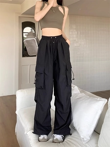 Detail of black cargo pants featuring functional side pockets and adjustable drawstring hem
