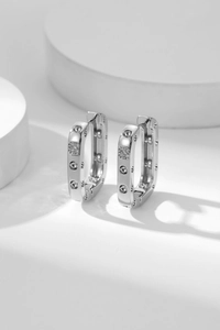 Detailed view of silver rectangular hoop earrings with cubic zirconia and textured dots