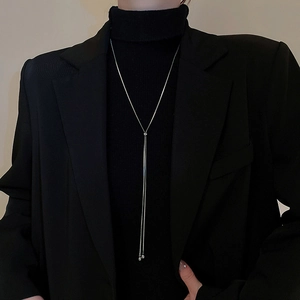 Collier long en Y argenté avec chaîne serpent sur un pull noir à col roulé