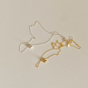 Close-up of polished gold and silver organic bean pendants on delicate bead chains