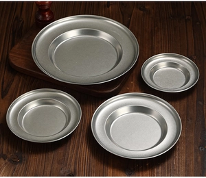 Deep stainless steel pasta plates with matte finish on a rustic dark wooden table