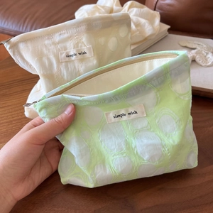 Macro detail of mint green and cream textured floral pouch with top zipper and label