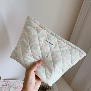 Detail of floral quilted cotton makeup bag featuring soft diamond stitching and cloth label