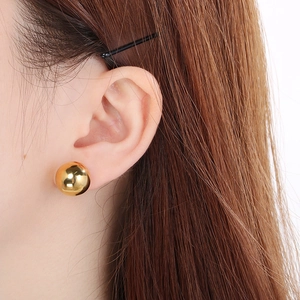 Close-up of a polished 18K gold-plated stainless steel hollow ball stud earring on ear