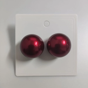 Close-up of deep red pearl-style round stud earrings on a white display card
